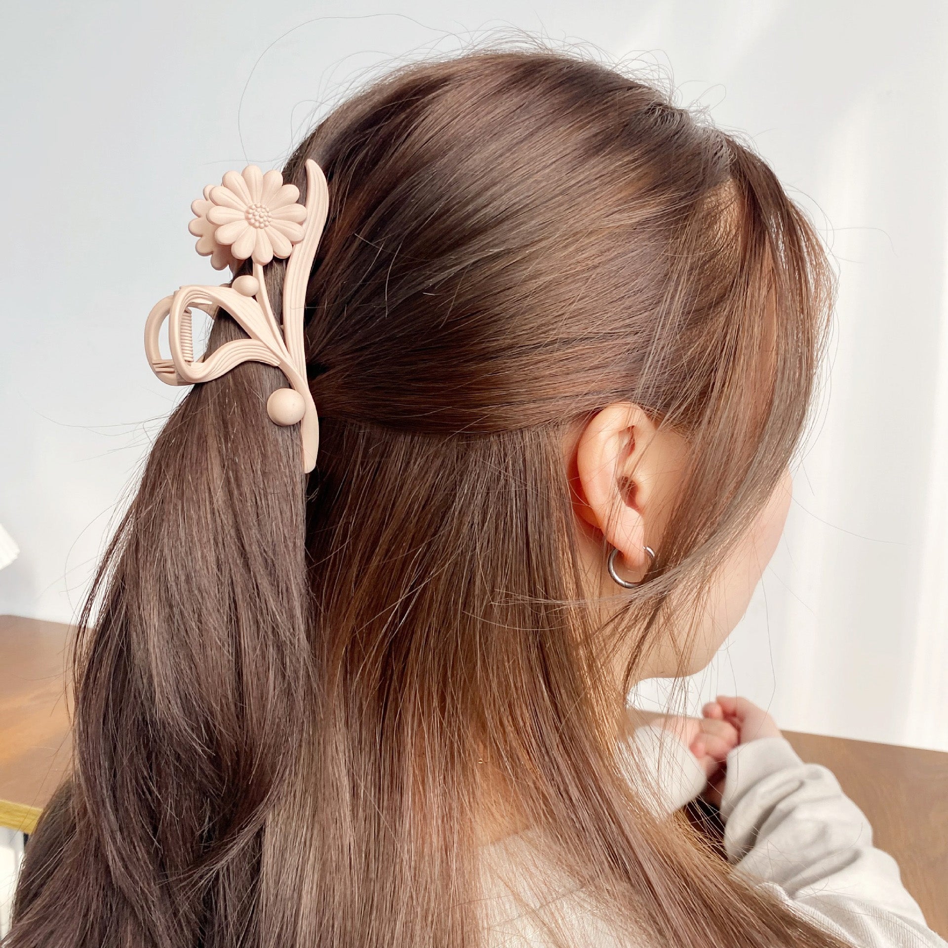 Beige daisy flower hair clip holding a ponytail