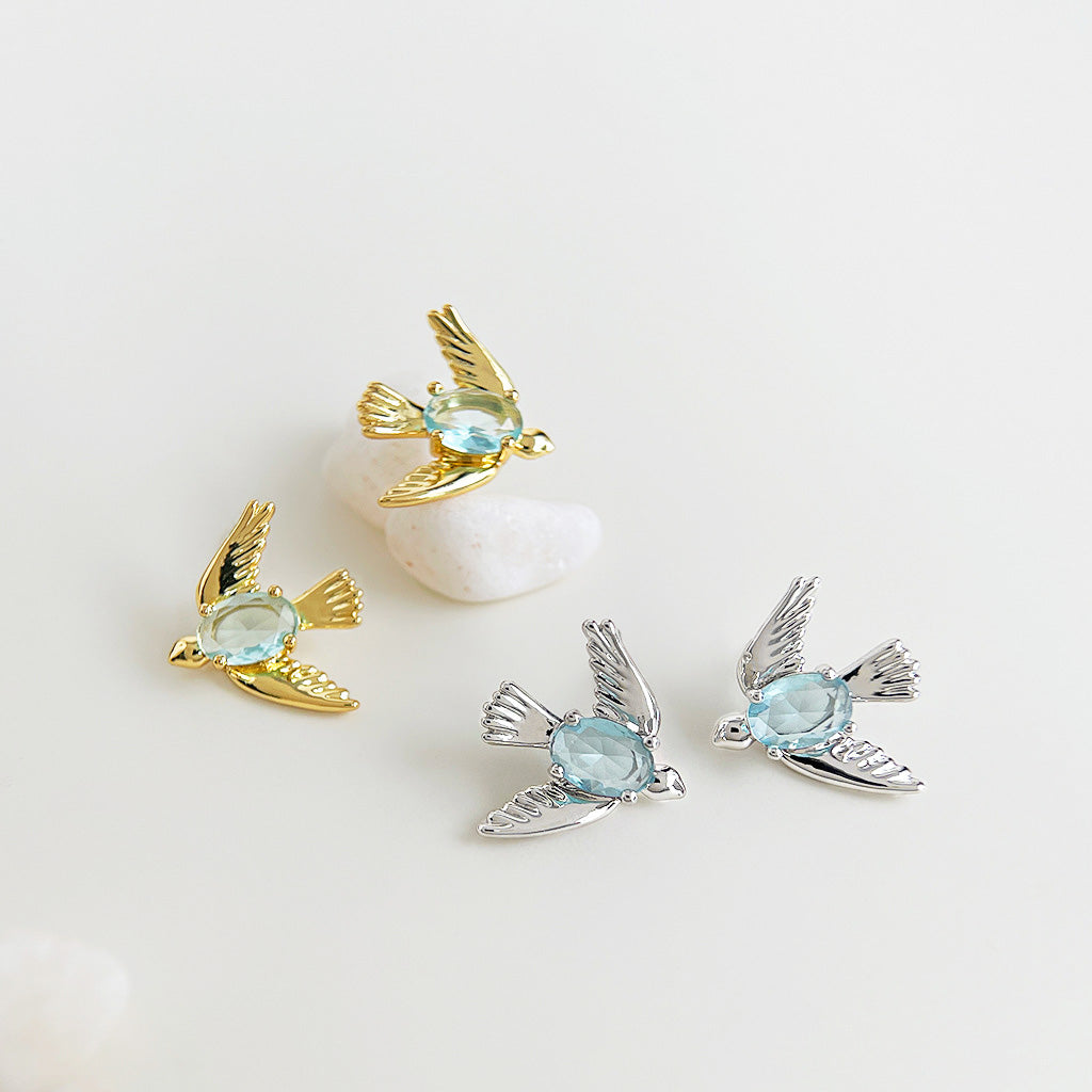 A detailed view of the 3D bird stud earrings in both gold and silver finishes.