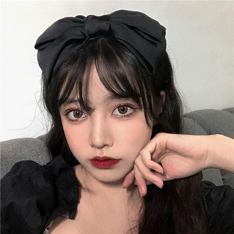 A classic black bow headband adding a touch of elegance to a simple outfit.