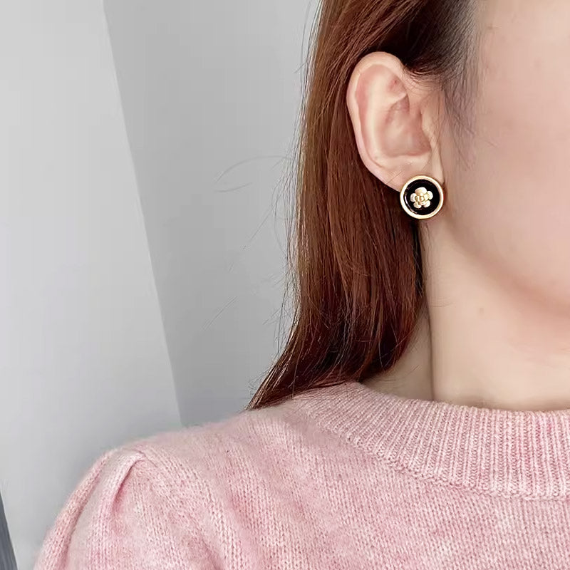 A model wearing the black and gold floral earring to demonstrate its elegant look.