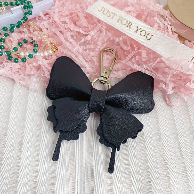 Close-up of the black faux leather bow bag charm with a gold clasp