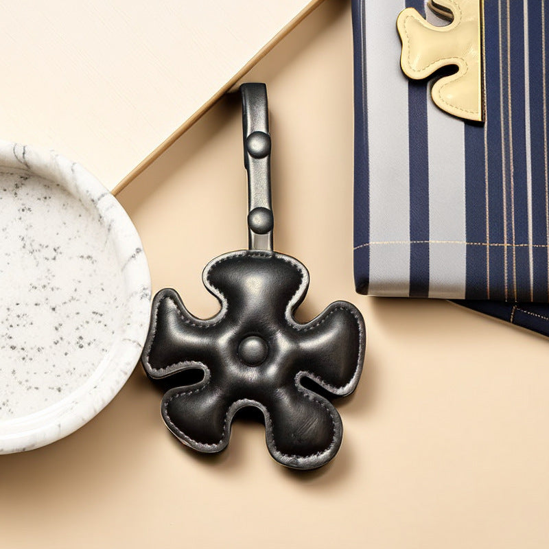 Black four-leaf clover leather keychain displayed in a stylish setting.