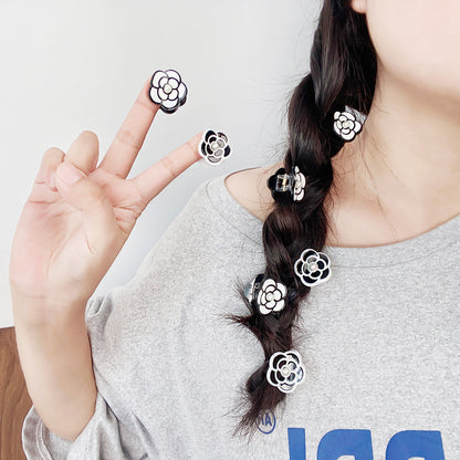 A black camellia flower hair clip styled in a braid, showcasing its use.
