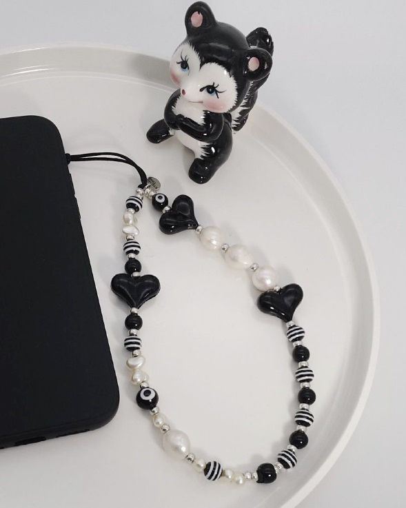 Detailed view of the beaded phone charm with a cat figurine