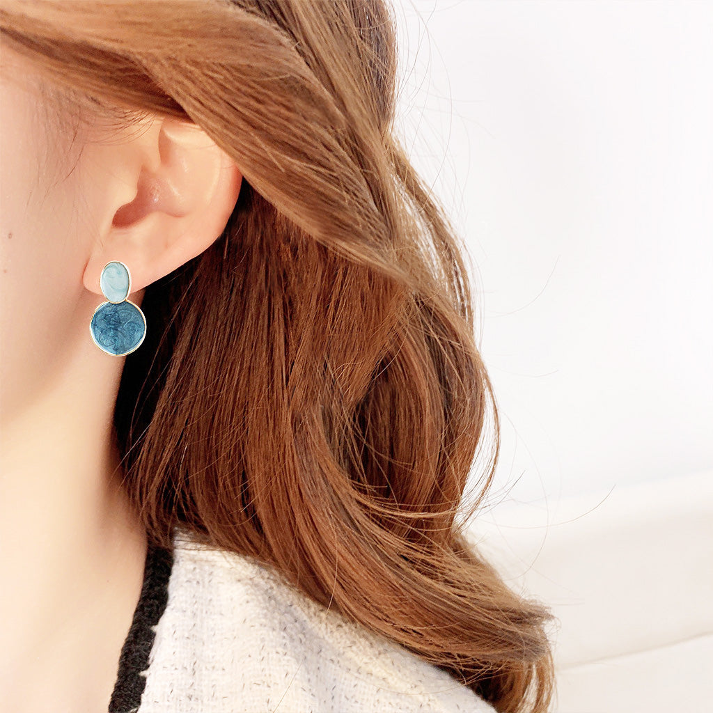 A woman wearing the stylish blue and gold dangle earrings, showing how they complement an outfit.