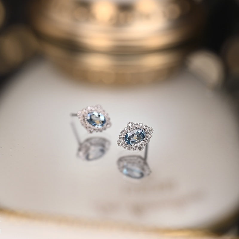 Close-up of the vintage rhombus stud earrings with a floral filigree design around the blue gemstone.