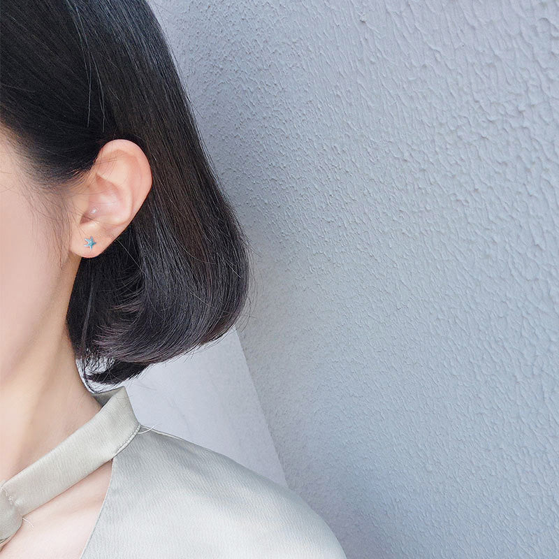 A woman wearing the tiny blue enamel starfish stud earring, highlighting its delicate design.