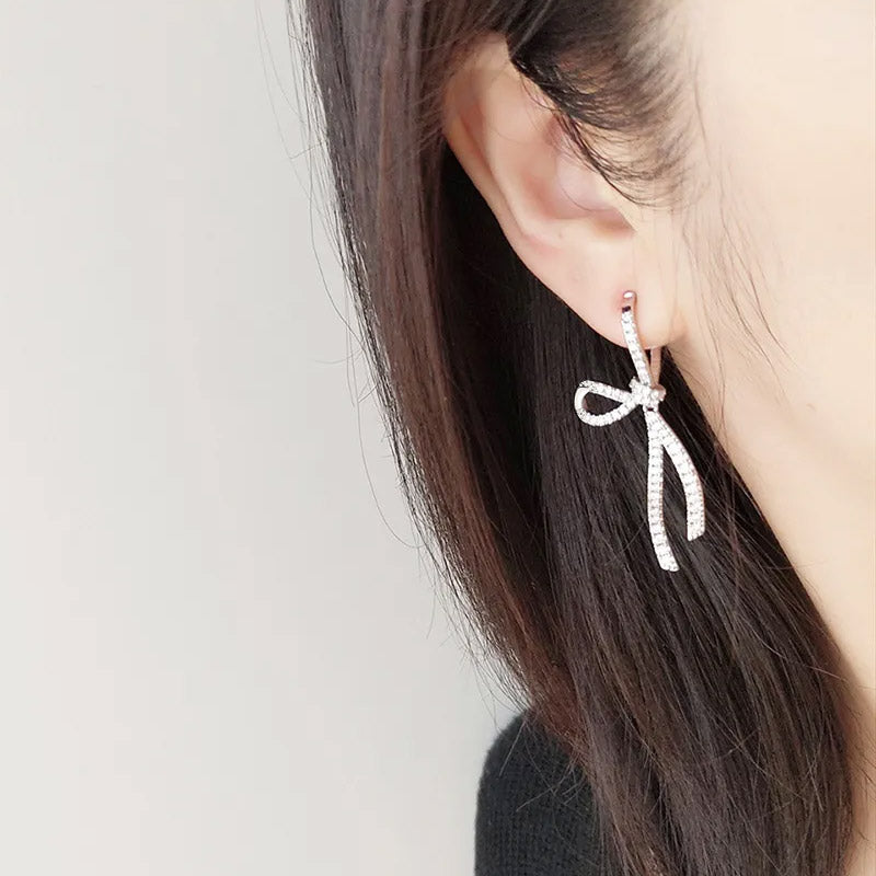Model showcasing the delicate fit of the sterling silver bow knot earrings