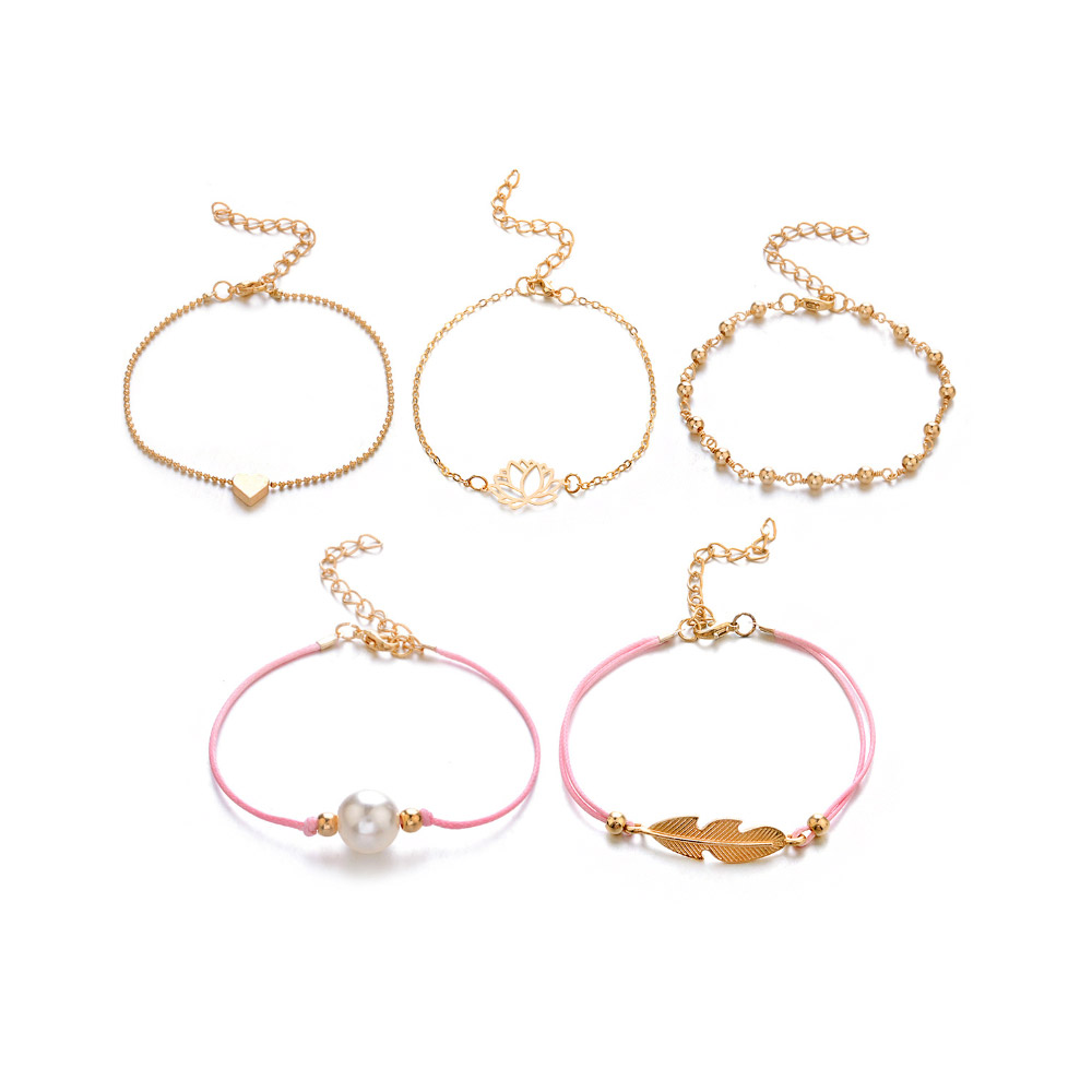 A detailed view of the gold and pink cord charm bracelets from the layering set.