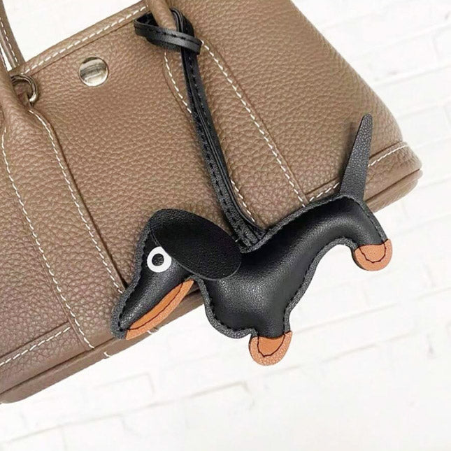 A brown dachshund leather charm attached to a handbag, showcasing its use as a stylish accessory.