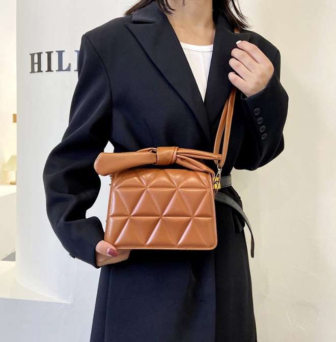 A model holding the brown version of the ribbon quilted PU leather handbag