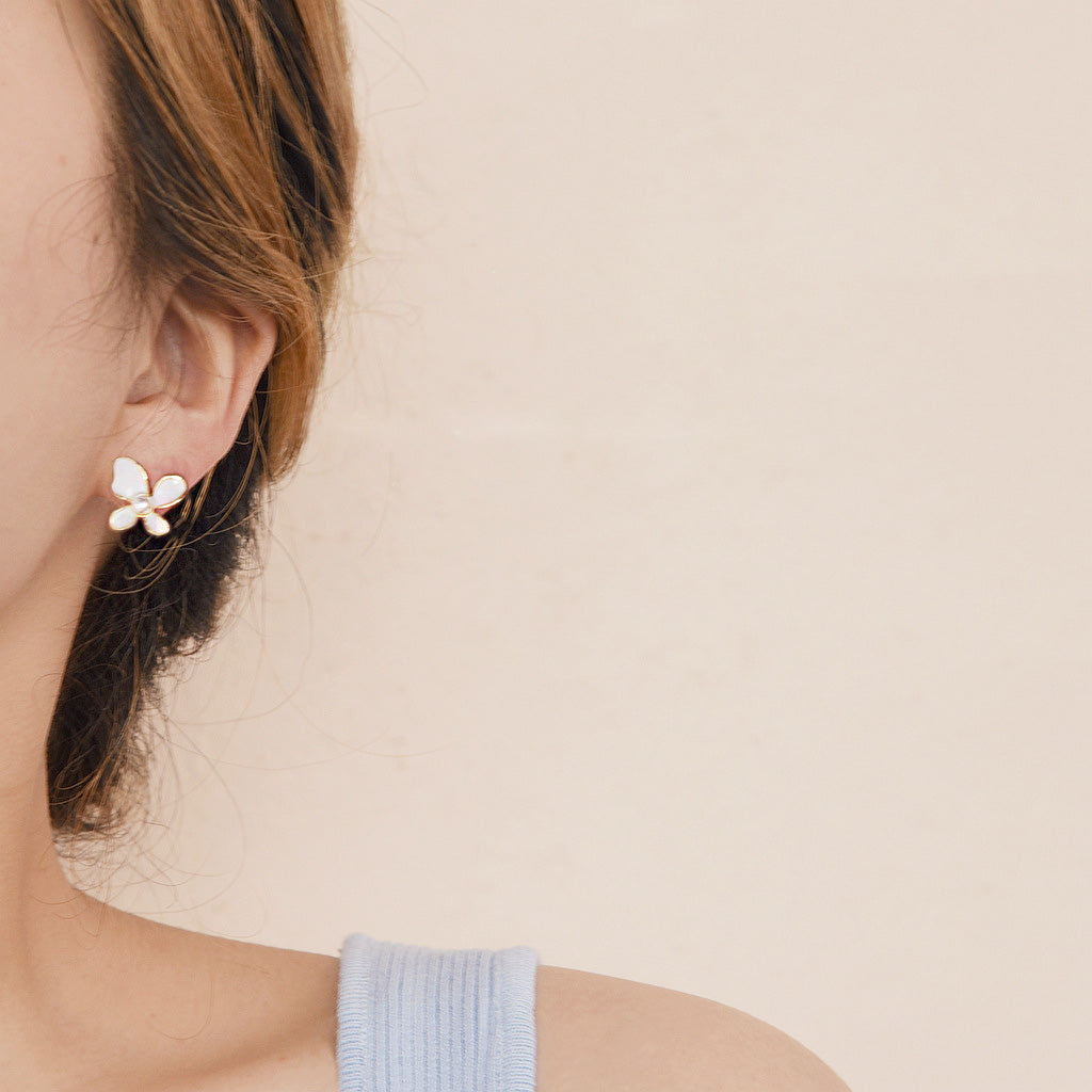 A model wearing the small white enamel butterfly earring with a pearl stud.