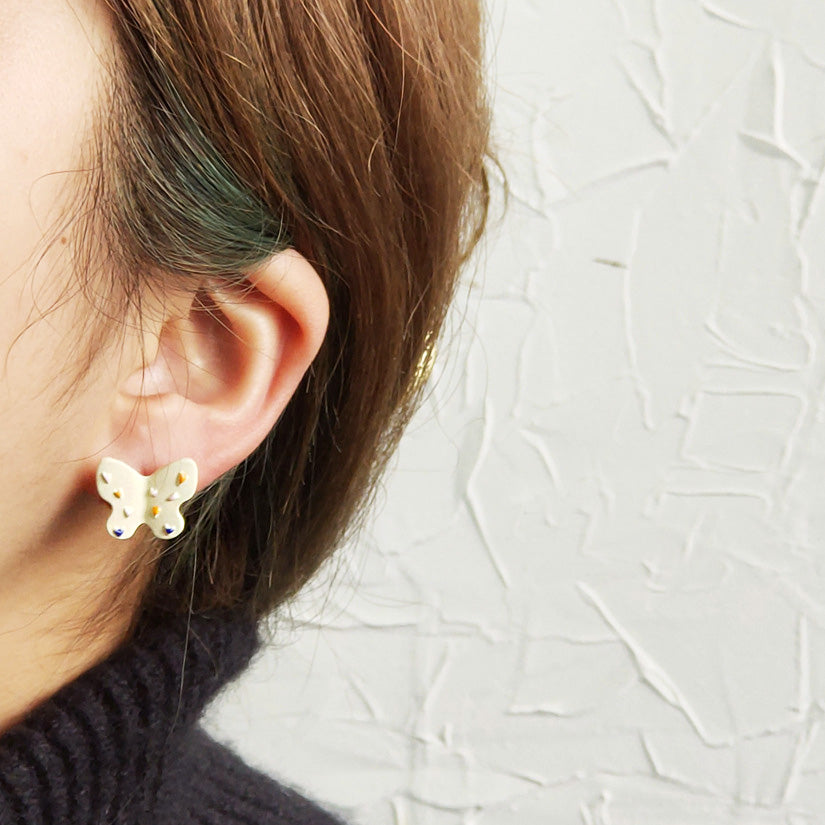 A model showcasing the white enamel butterfly earring in her ear.