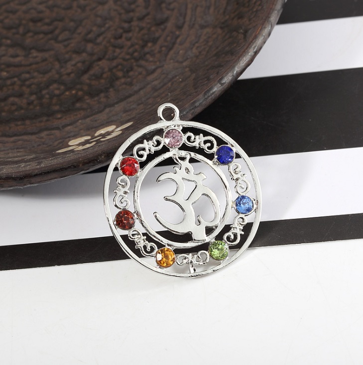Close-up of a custom Om symbol chakra pendant with seven colored gemstones
