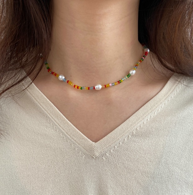 A model showcasing the colorful beaded pearl necklace with a cream sweater.
