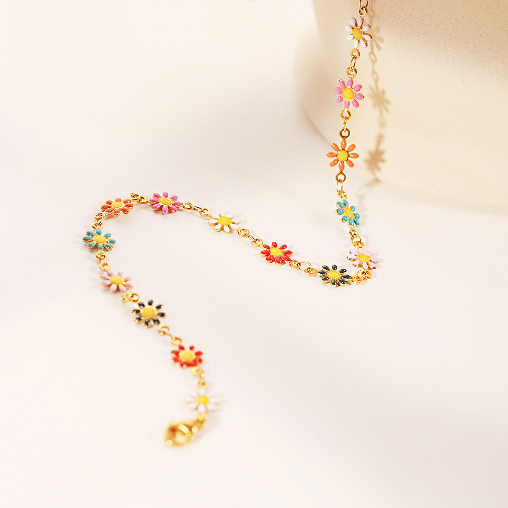 A detailed view of the colorful enamel daisy charms on the gold chain necklace.