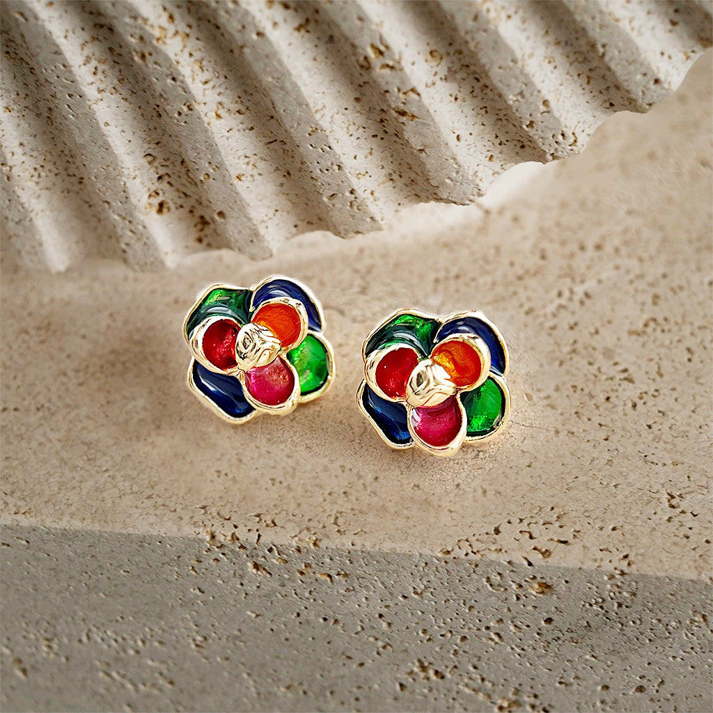 A detailed shot of the multi-color enamel flower earrings on a decorative stone.