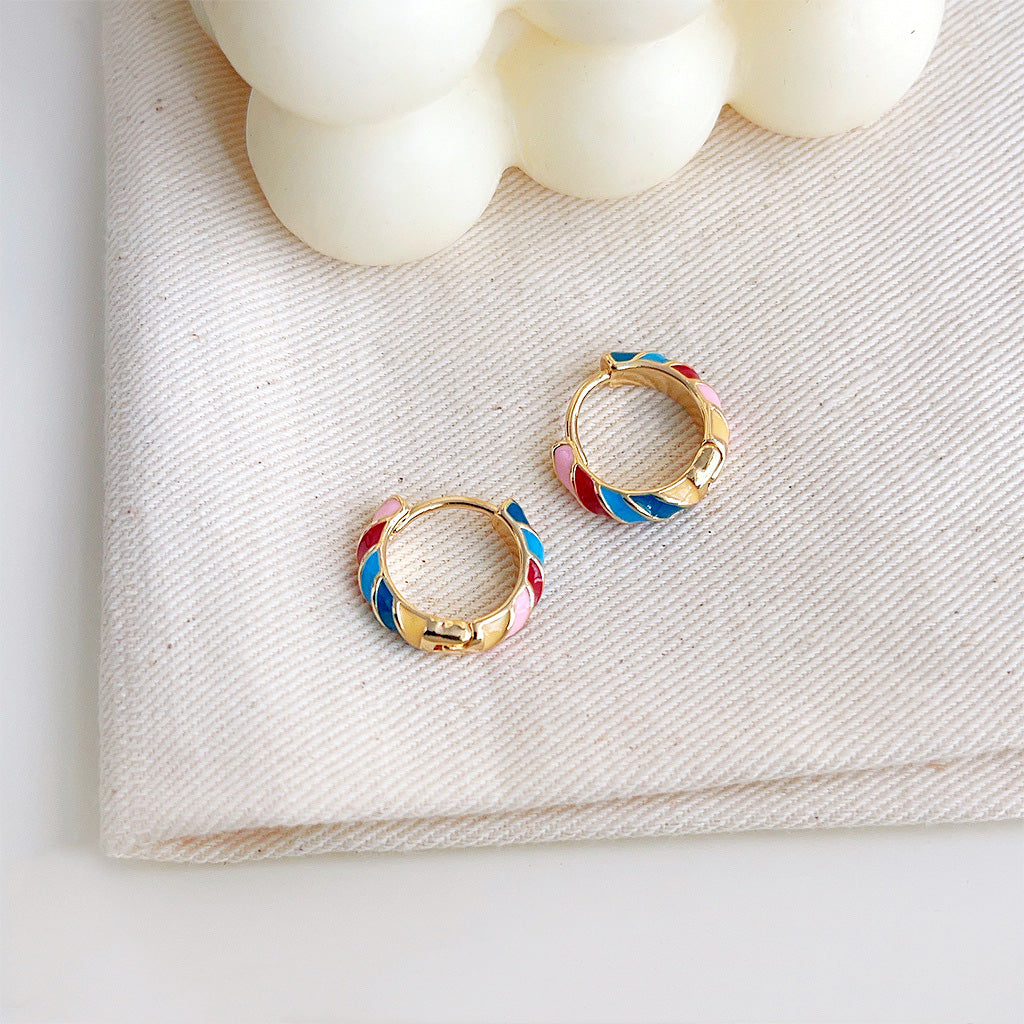 A collection of colorful enamel huggie hoop earrings displayed together.