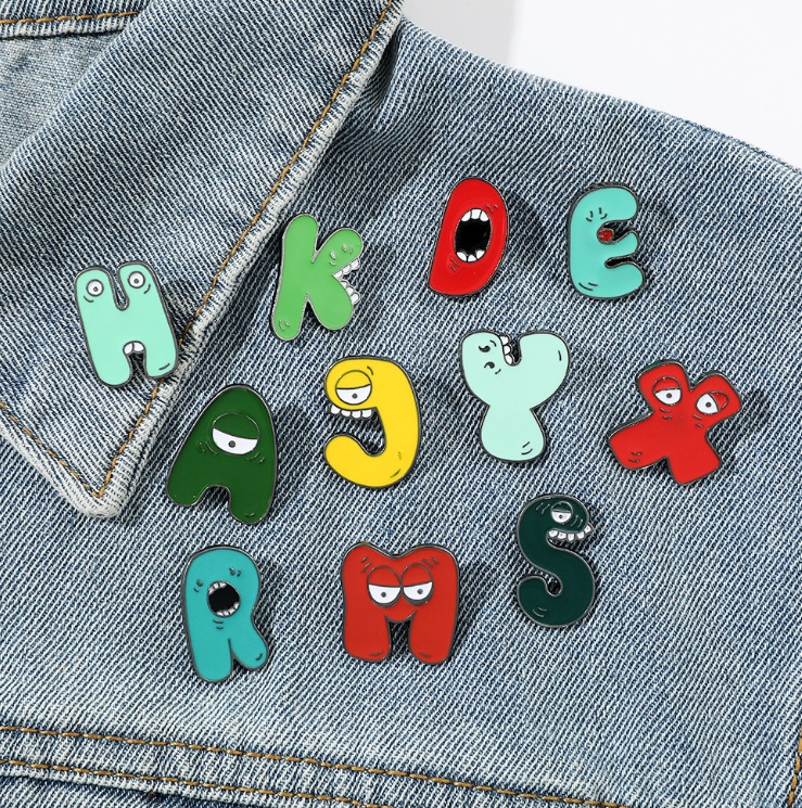 Custom enamel letter pins shown on a denim jacket for a personalized style.