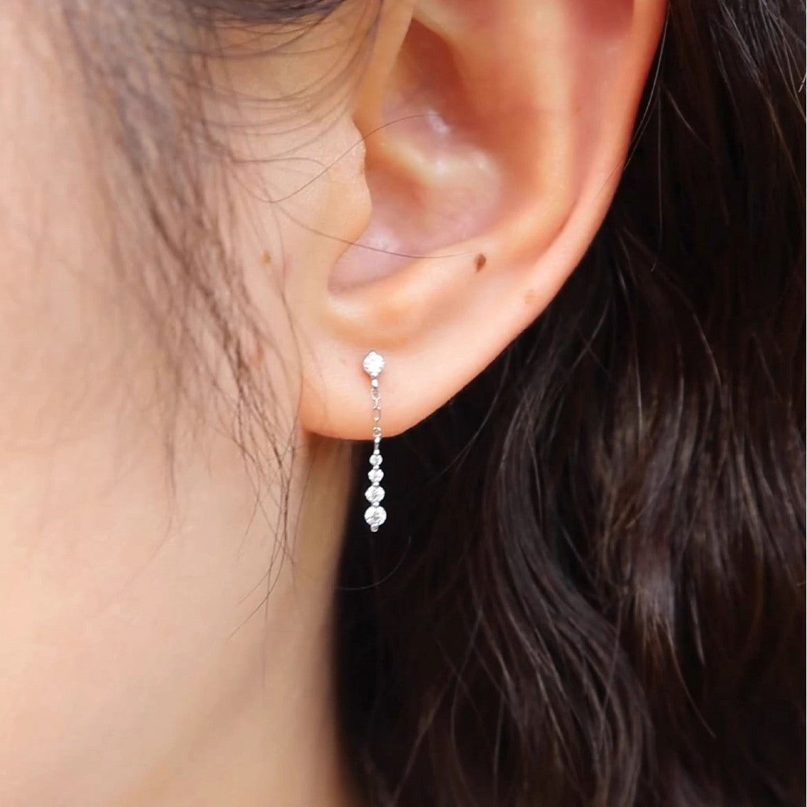 Model showcasing the elegant dangle and sparkle of the white gold plated CZ chain drop earrings.