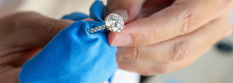 A person cleaning a diamond ring, demonstrating proper jewelry care.