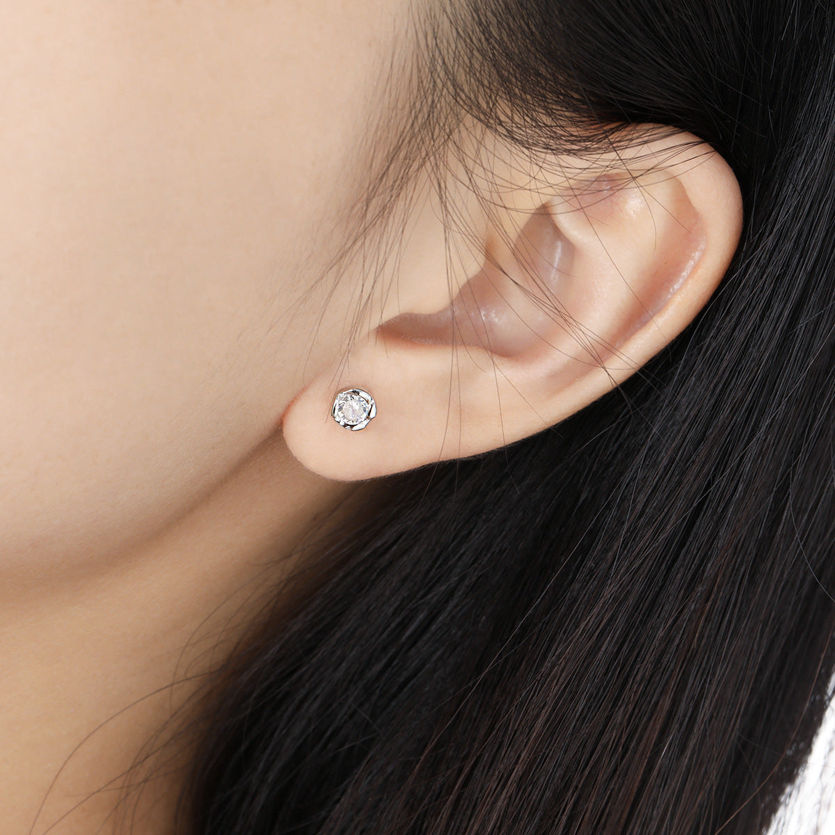 Close-up image of small cubic zirconia stud earrings on ear, 925 sterling silver earrings wholesale for women minimalist style.