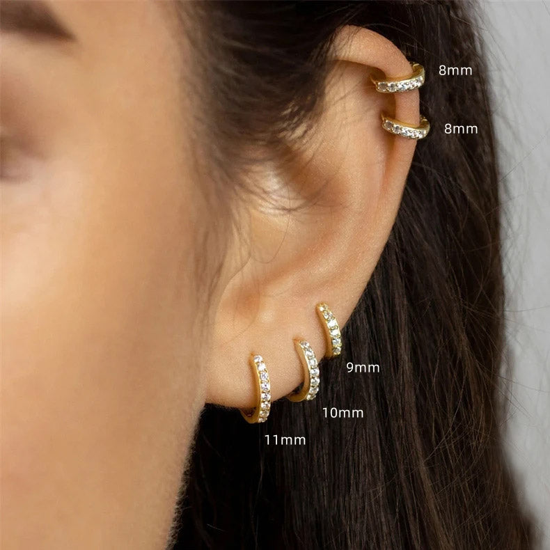 Model wearing various sizes of zircon huggie hoop earrings to show scale