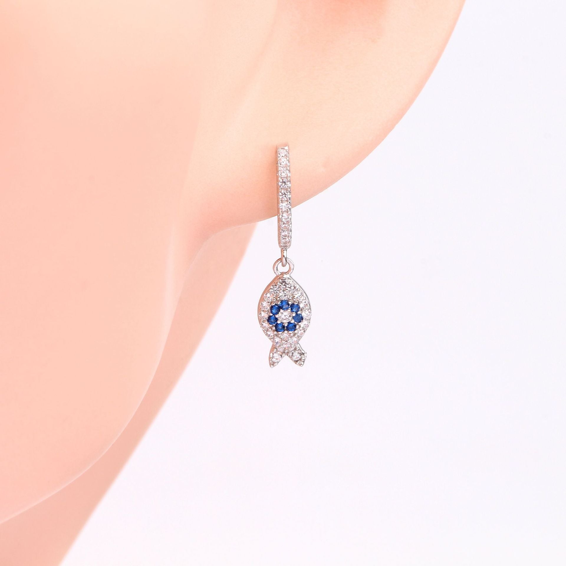 Close-up of a sterling silver fish earring with blue gemstones