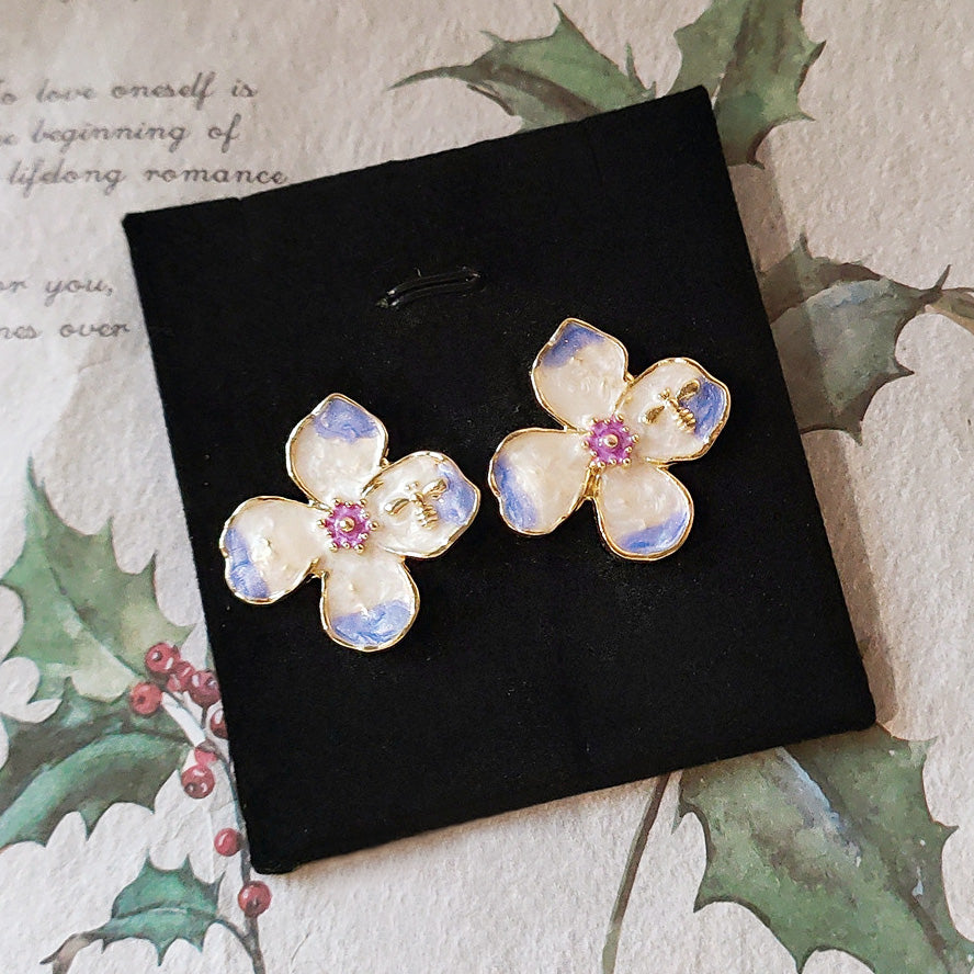 Detailed view of the flower earrings showing the gold bee accent