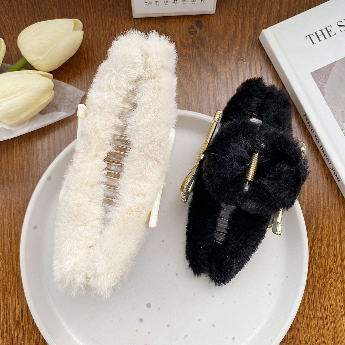 A stylish arrangement of white and black fuzzy hair clips on a decorative plate.