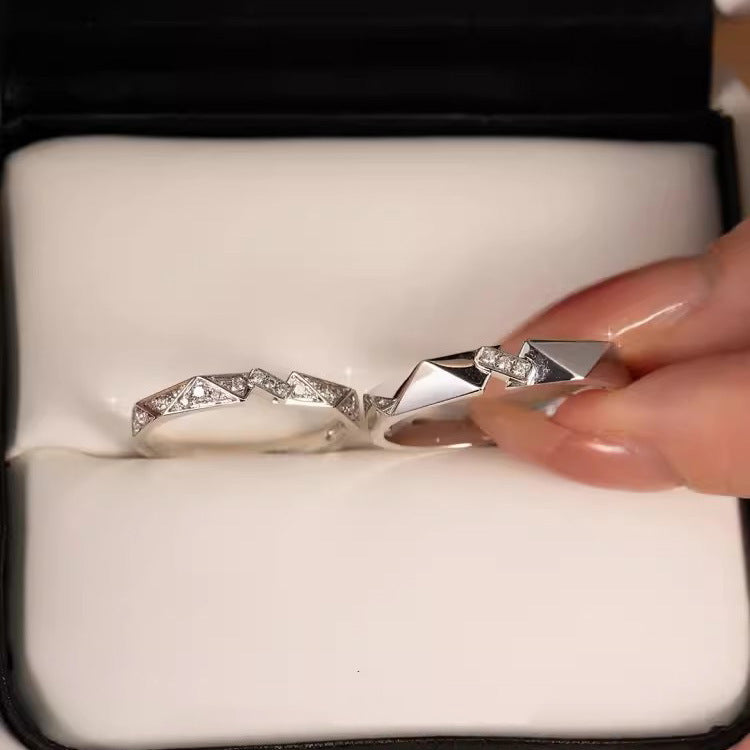 A close-up of the matching silver origami rings with cubic zirconia stones, displayed in a jewelry box.