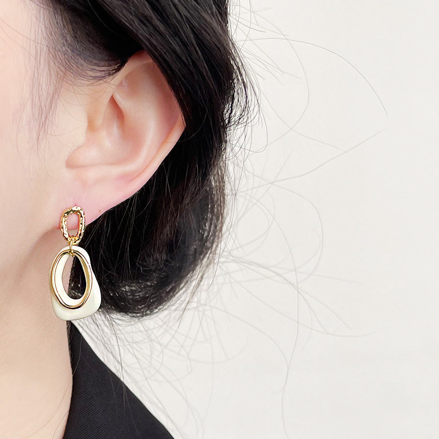 A model wearing the geometric white enamel and gold drop earring.