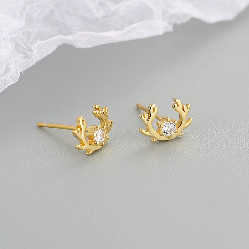 A pair of gold antler stud earrings with clear zircon gemstones shown against a white background.