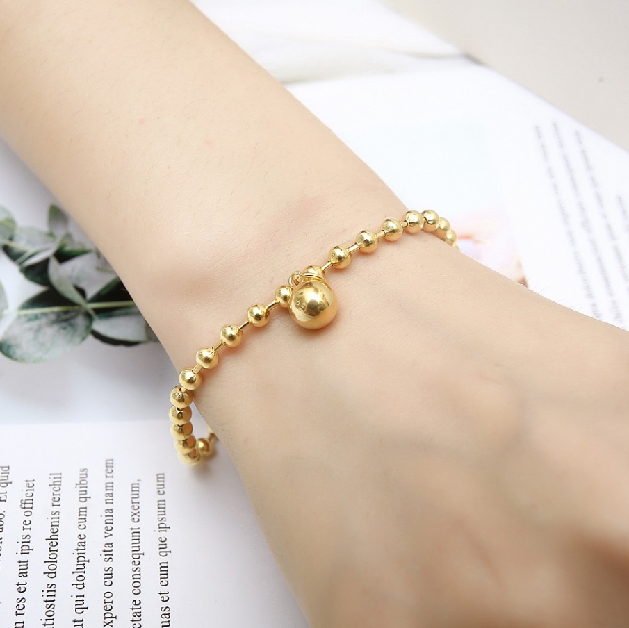 A model wearing the golden bead bracelet to showcase its elegant fit.
