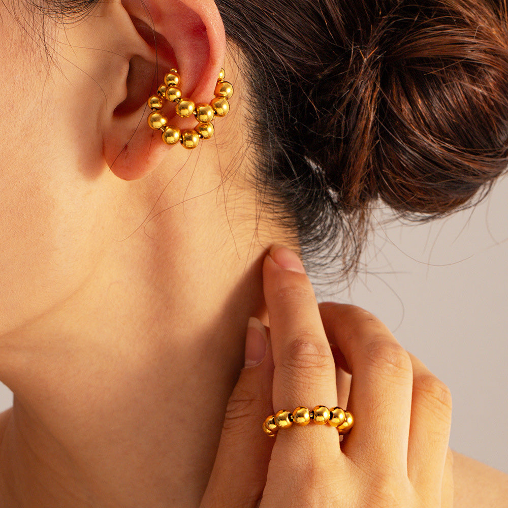 Detailed view of the gold beaded ring and a matching earring