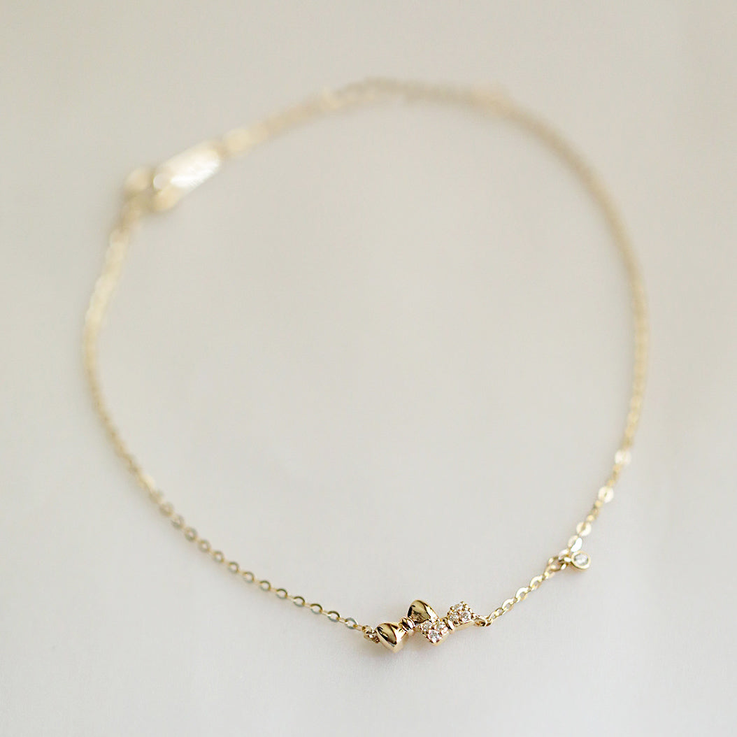 Detailed product shot of the gold-colored double bow knot charm bracelet