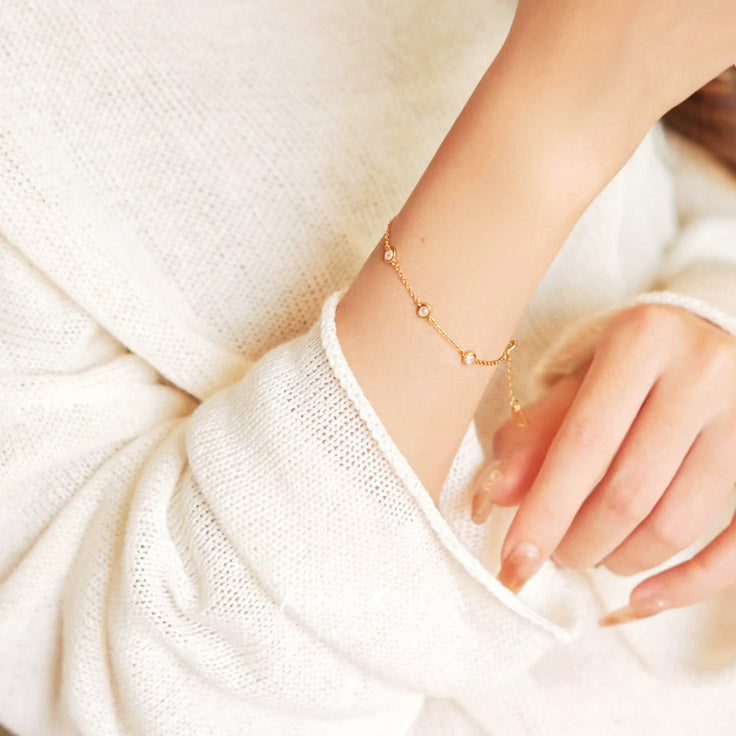 A detailed view of the bezel-set opal bracelet on a woman's wrist, showing its delicate design.