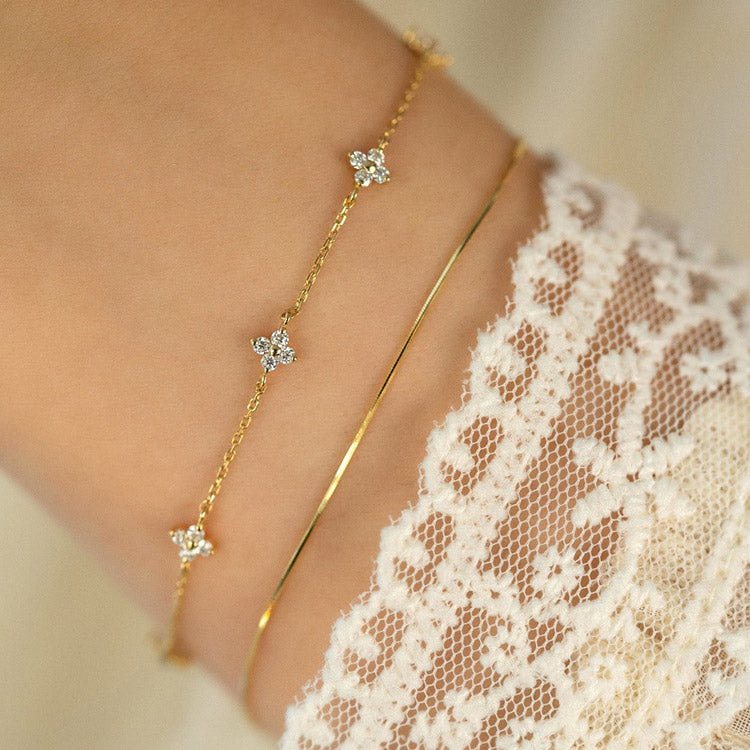 A model's wrist adorned with the layered 18k gold plated zircon flower bracelets.