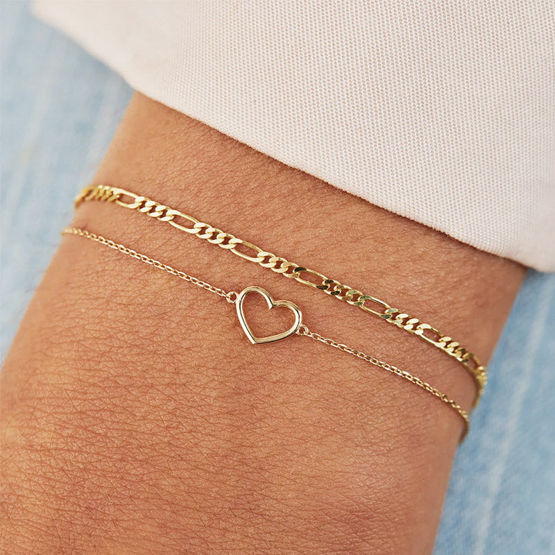 A model's wrist adorned with the 925 sterling silver hollow heart chain bracelet in gold.