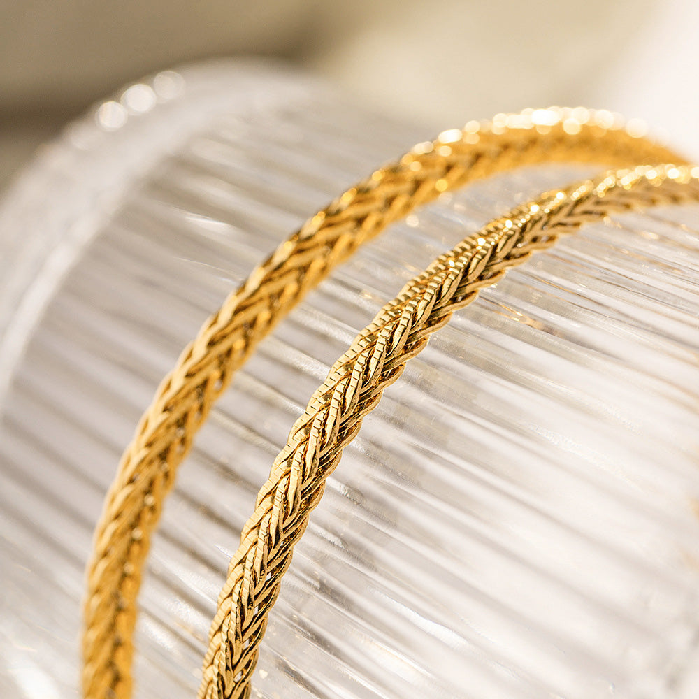 A collection of five gold-plated stainless steel curb chain bracelets arranged neatly.