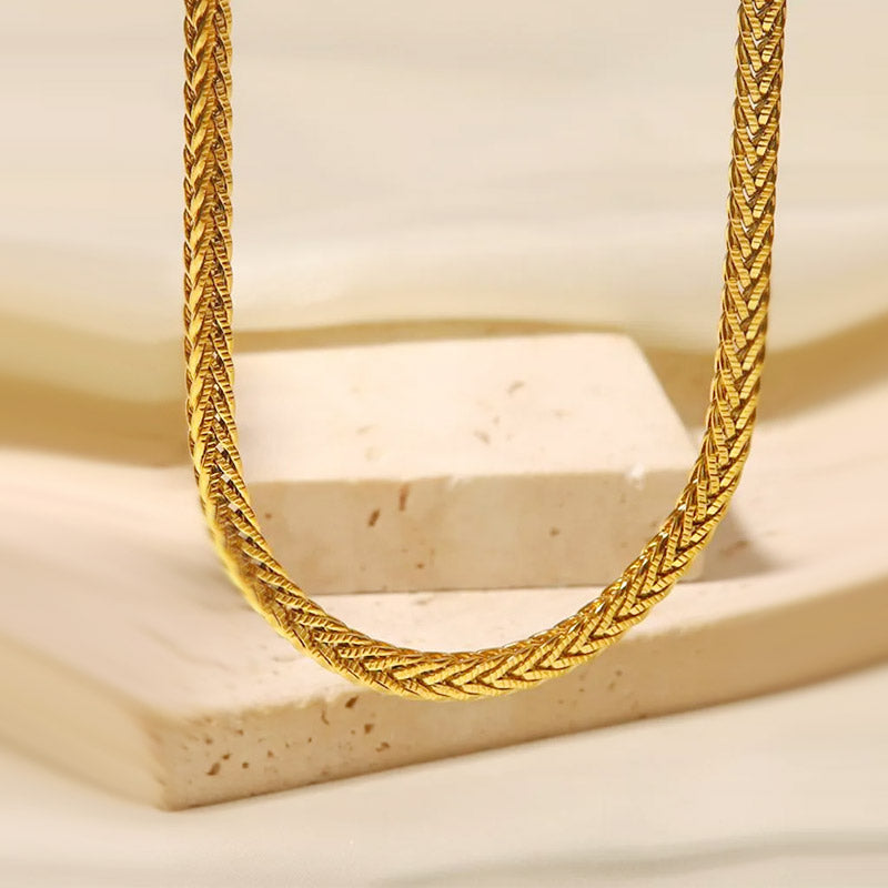 Gold twisted rope necklace displayed on a stone for a sophisticated product shot