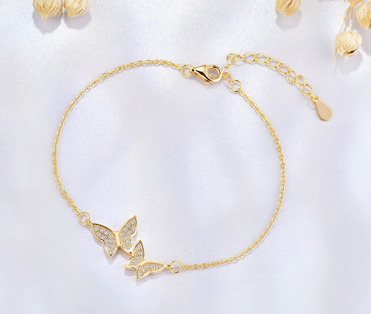A close-up of the gold butterfly bracelet with its sparkling zircon pendant.