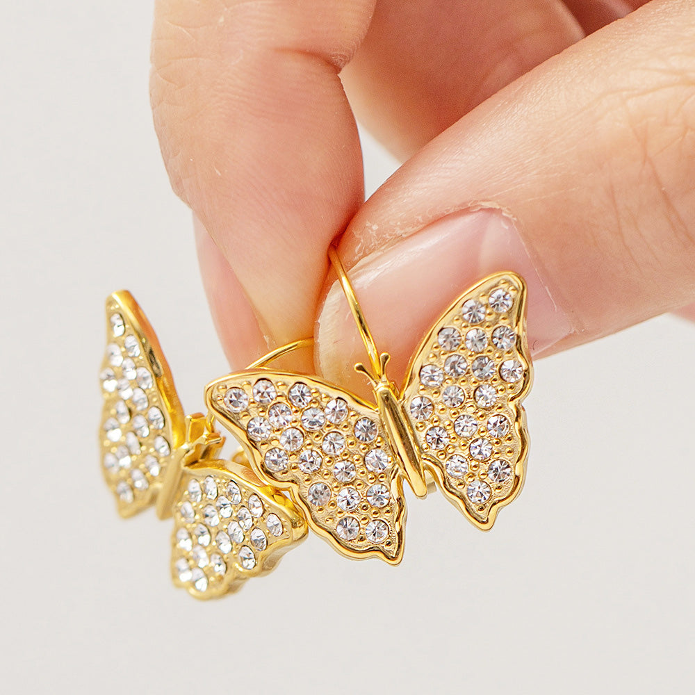 Close-up of the gold butterfly earring held in hand