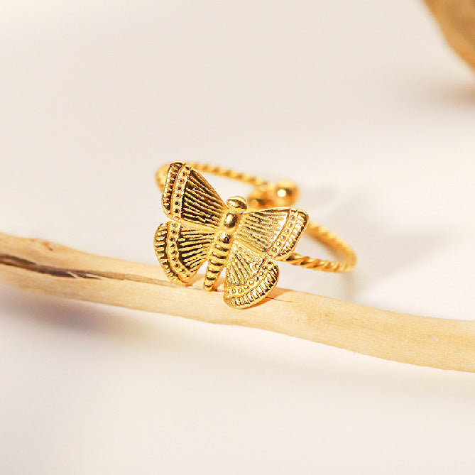 Close-up product shot of the gold butterfly ring showing its textured details.