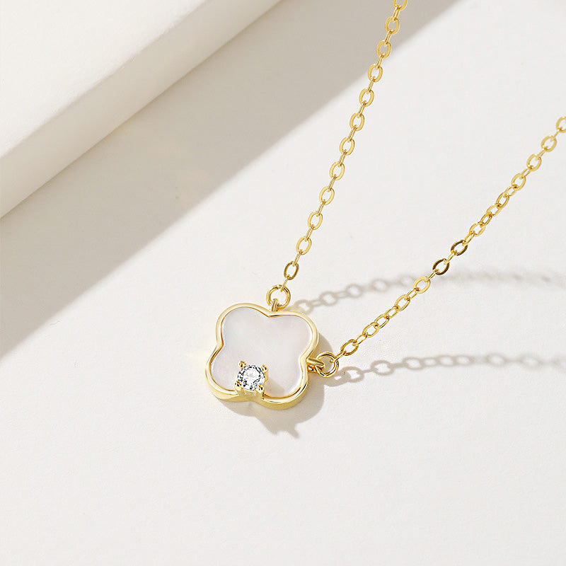 A detailed shot of the mother-of-shell four-leaf clover pendant on a gold-finished chain