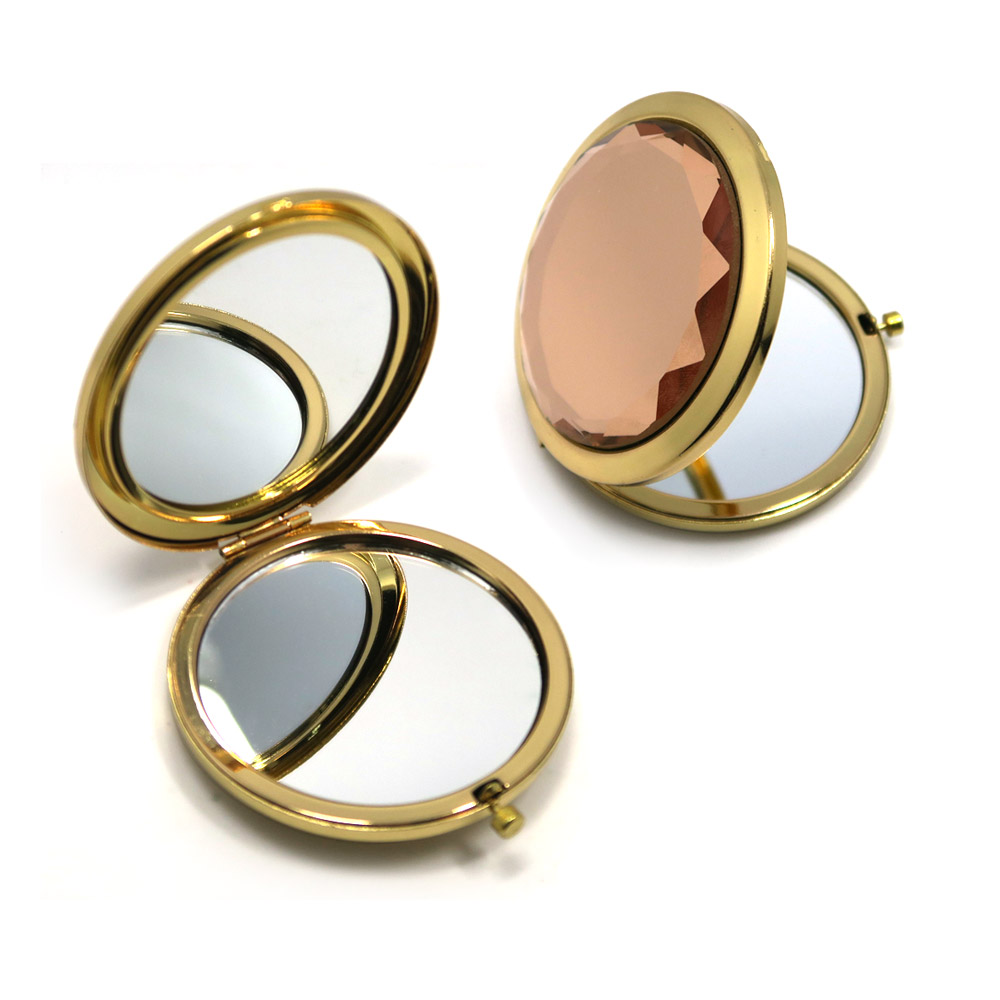 An open and closed view of the gold compact mirror with a pink gemstone cover