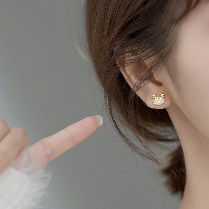 Gold variant of the sterling silver crab stud earring being worn.