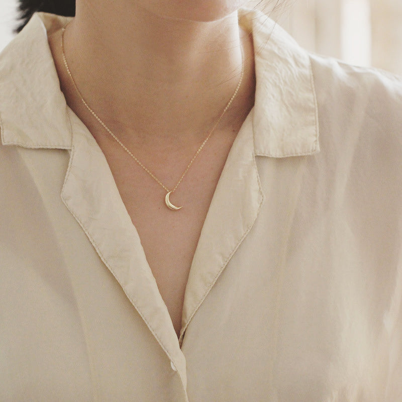 A woman wearing the gold crescent moon pendant necklace, highlighting its elegant drape.