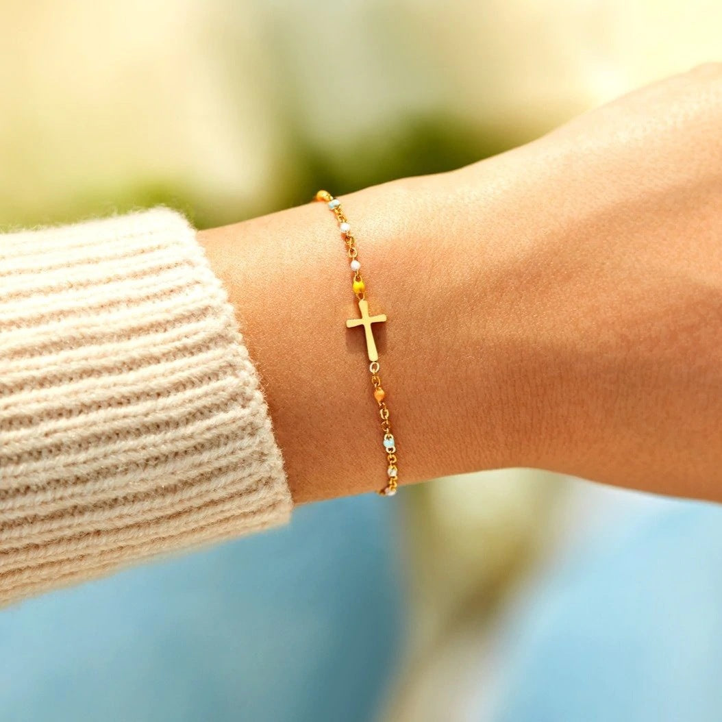 Gold cross bracelet worn on a wrist to show its elegant style