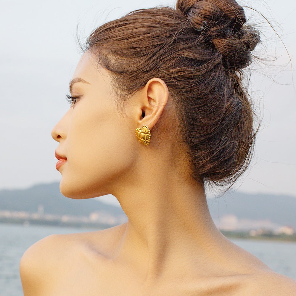 A woman models the gold heart-shaped stud earring, highlighting its elegant look.